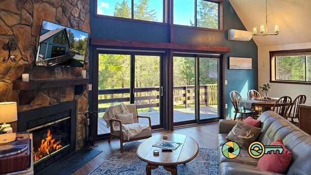 A spacious living room with a stone fireplace, large windows, and a cozy seating area.