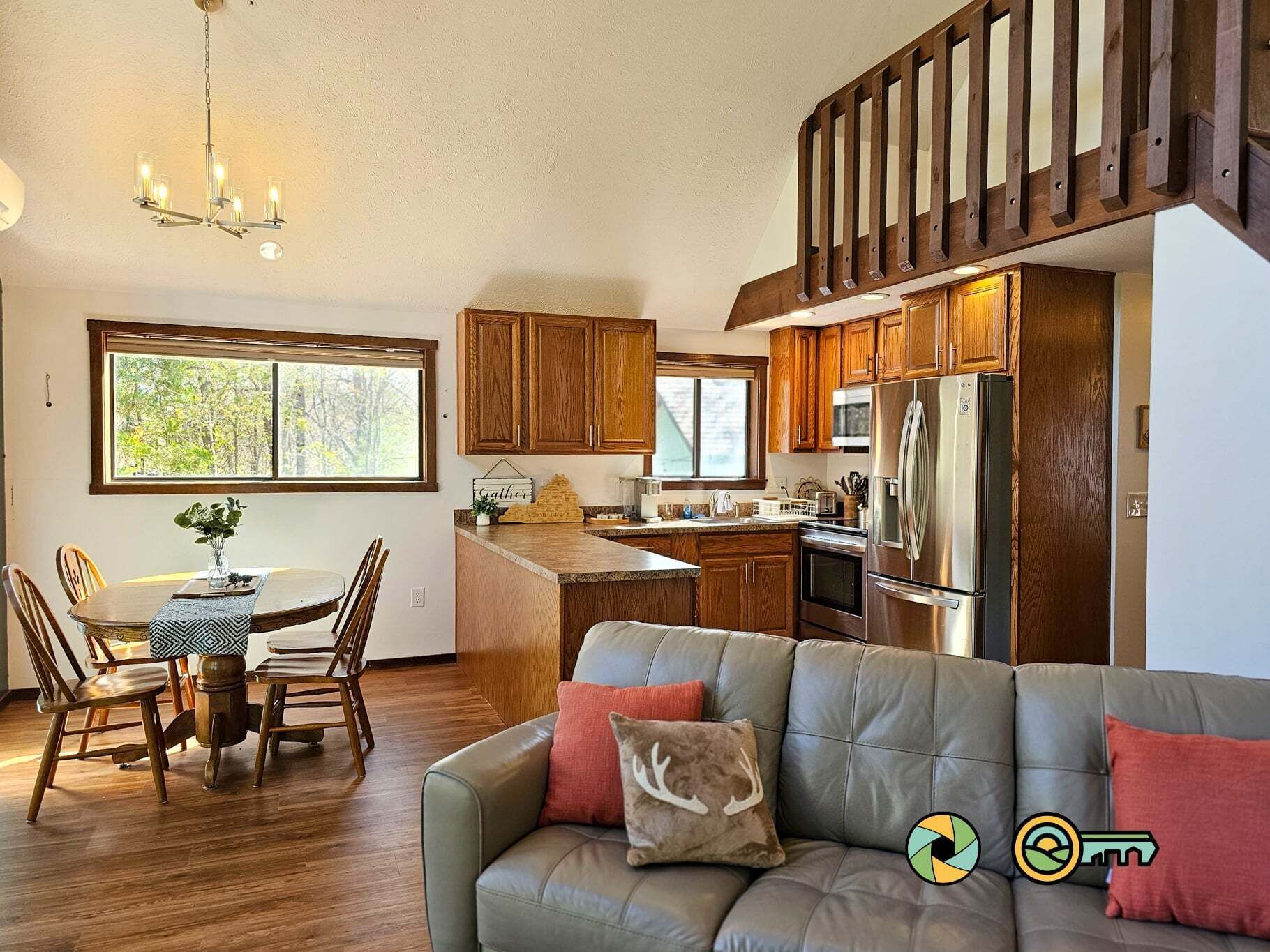 A modern kitchen with wooden cabinets, a stainless steel refrigerator, and a dining area with a table and chairs.