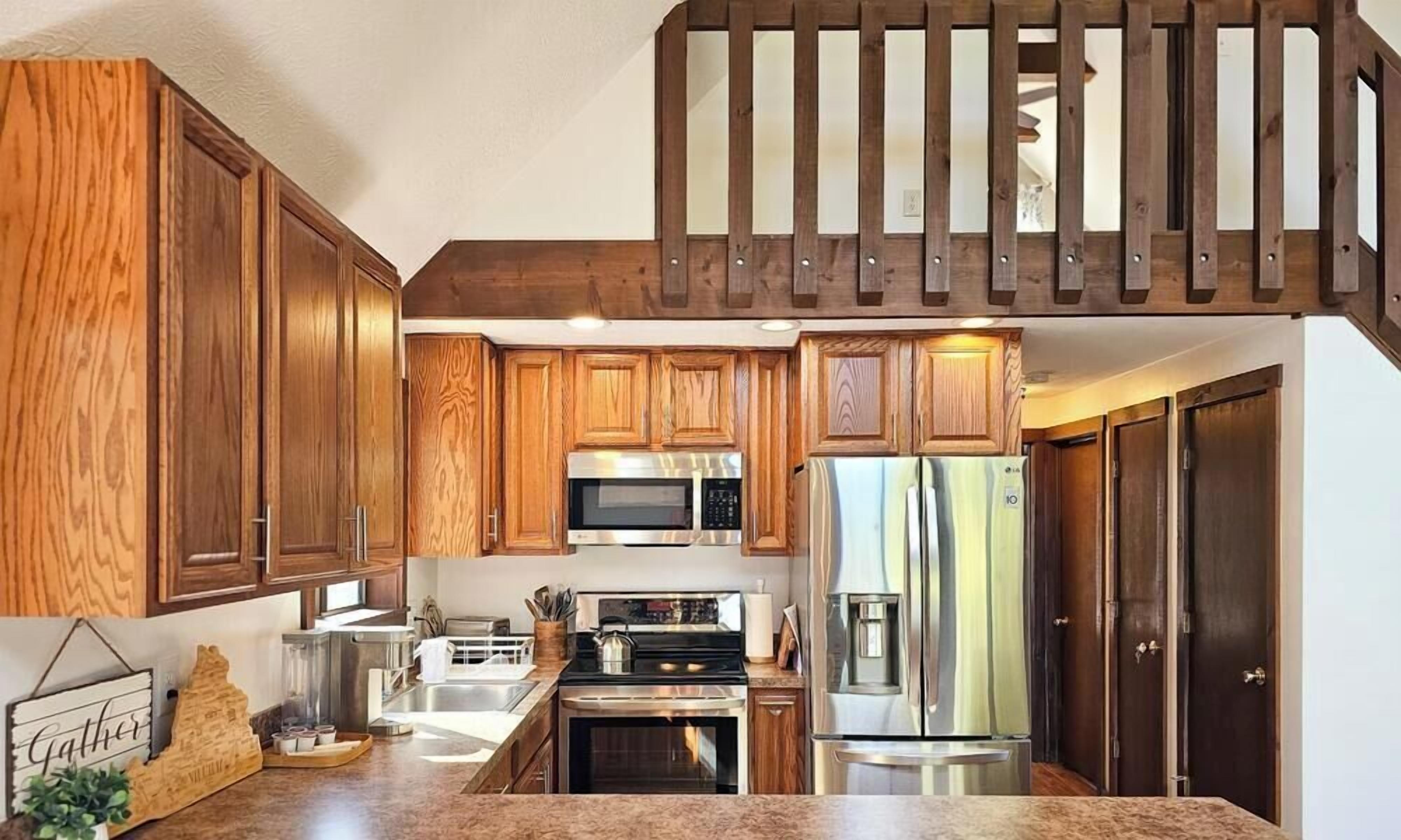 Une cuisine avec des meubles en bois, des appareils électroménagers en acier inoxydable et un escalier en bois.