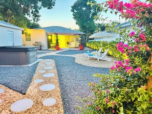 A patio area with a hot tub, lounge chairs, and a pathway with circular stepping stones. - Italian Amalfi Cottage in FL - Beach Walk - Hot Tub (Lake Worth Beach)
