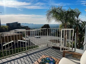 Une terrasse sur le toit offrant une vue sur les gratte-ciel de la ville, avec une rambarde en métal et un banc en bois.