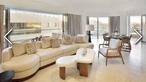 Un salon moderne avec un canapé, des fauteuils, une table à manger et une vue sur le balcon.