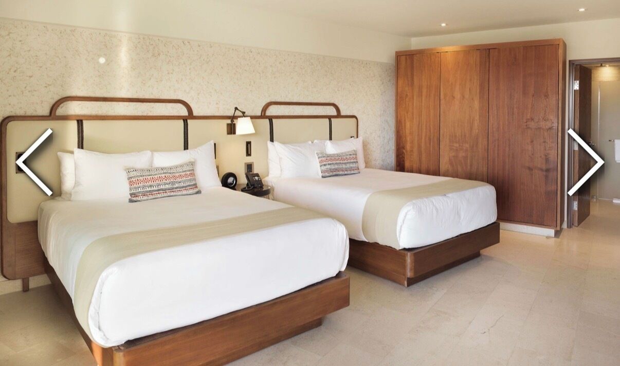 Une chambre d’hôtel avec deux lits, une armoire en bois et une porte de salle de bain.
