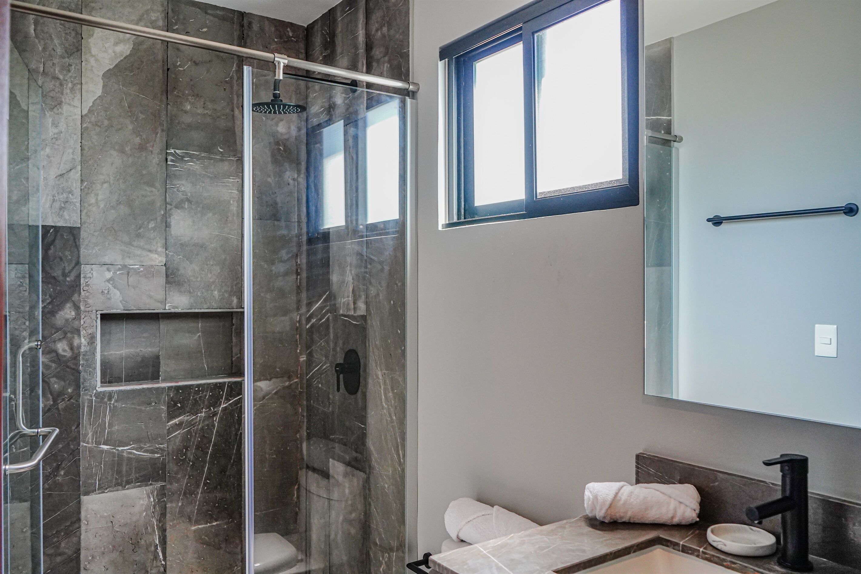 Une salle de bain moderne avec une douche à parois de verre, un grand miroir et un porte-serviettes.