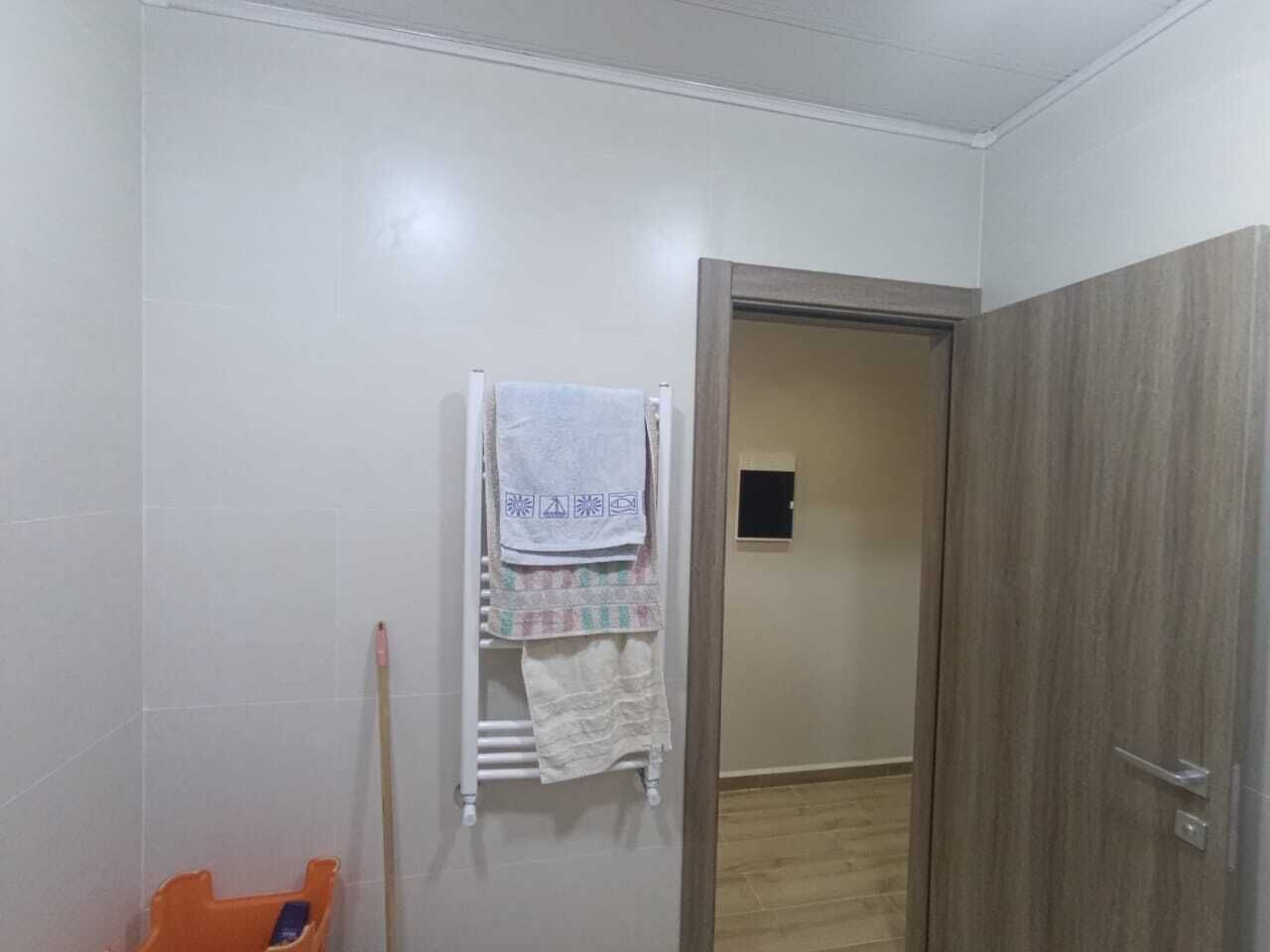 A bathroom with a towel rack, a wooden door, and a small window.