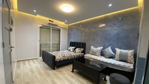 A bedroom with a bed, a sofa, a coffee table, and a small stool. - Résidence Oasis (Filfila)