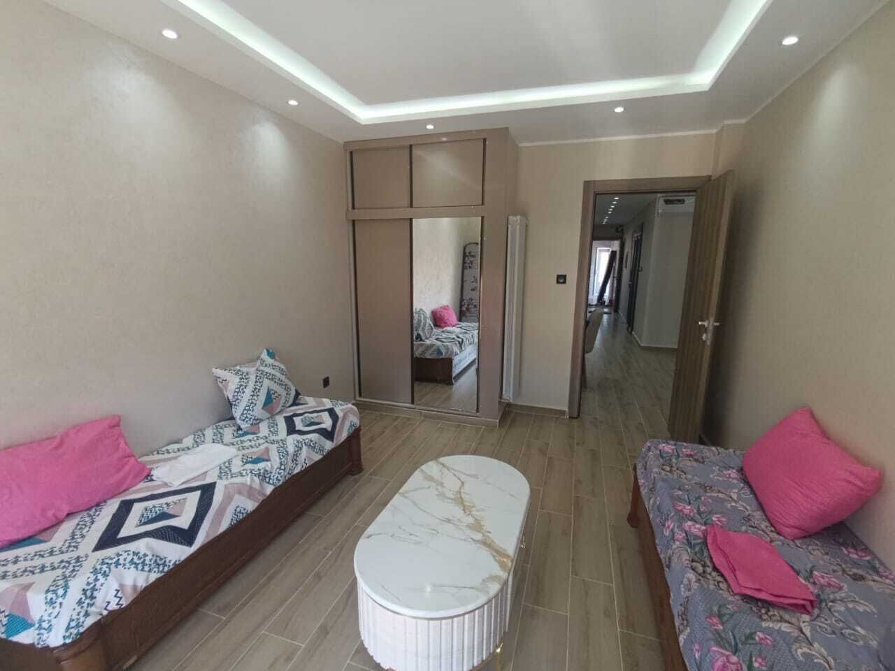 A modern bedroom with a bed, a sofa, a mirror, and a small table.