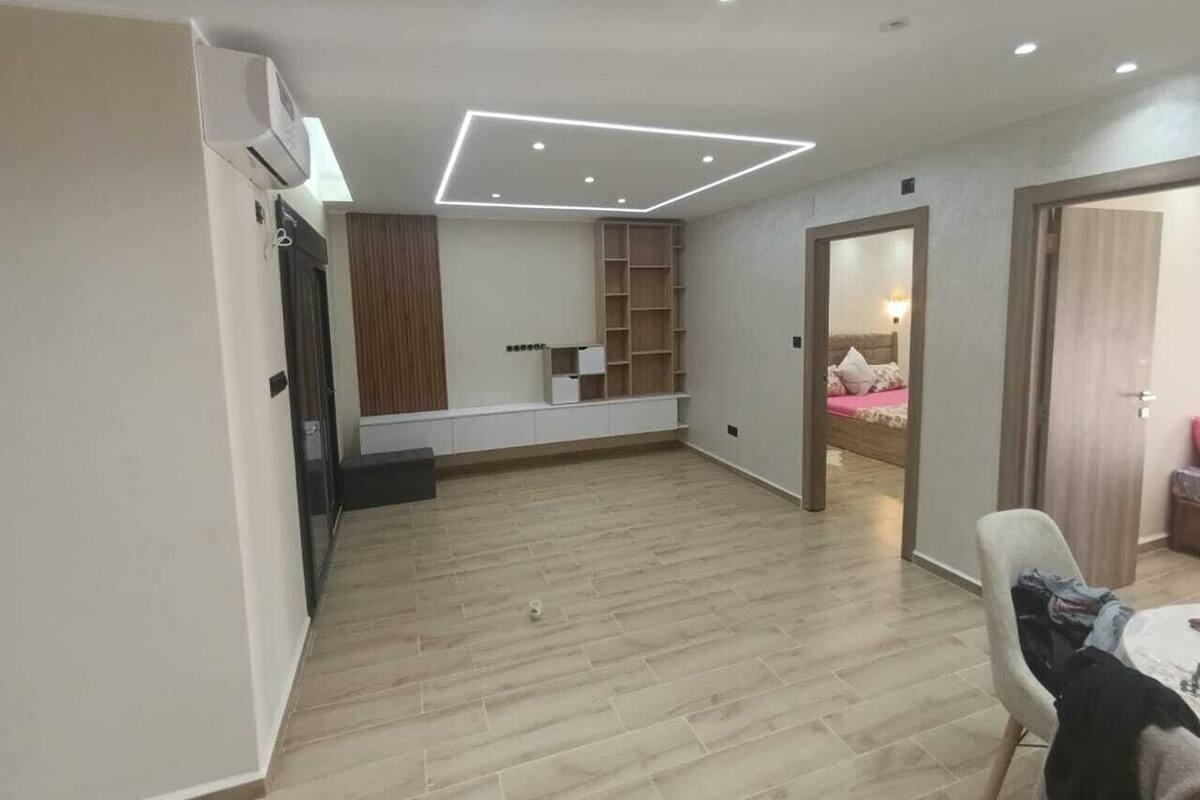 A spacious room with a built-in wardrobe, a seating area with a table, and a bed in the background.