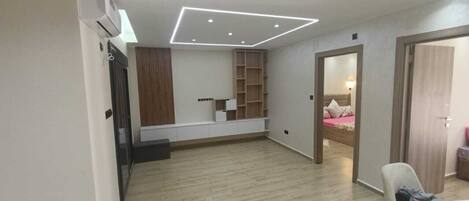 A spacious room with a built-in wardrobe, a seating area with a table, and a bed in the background.