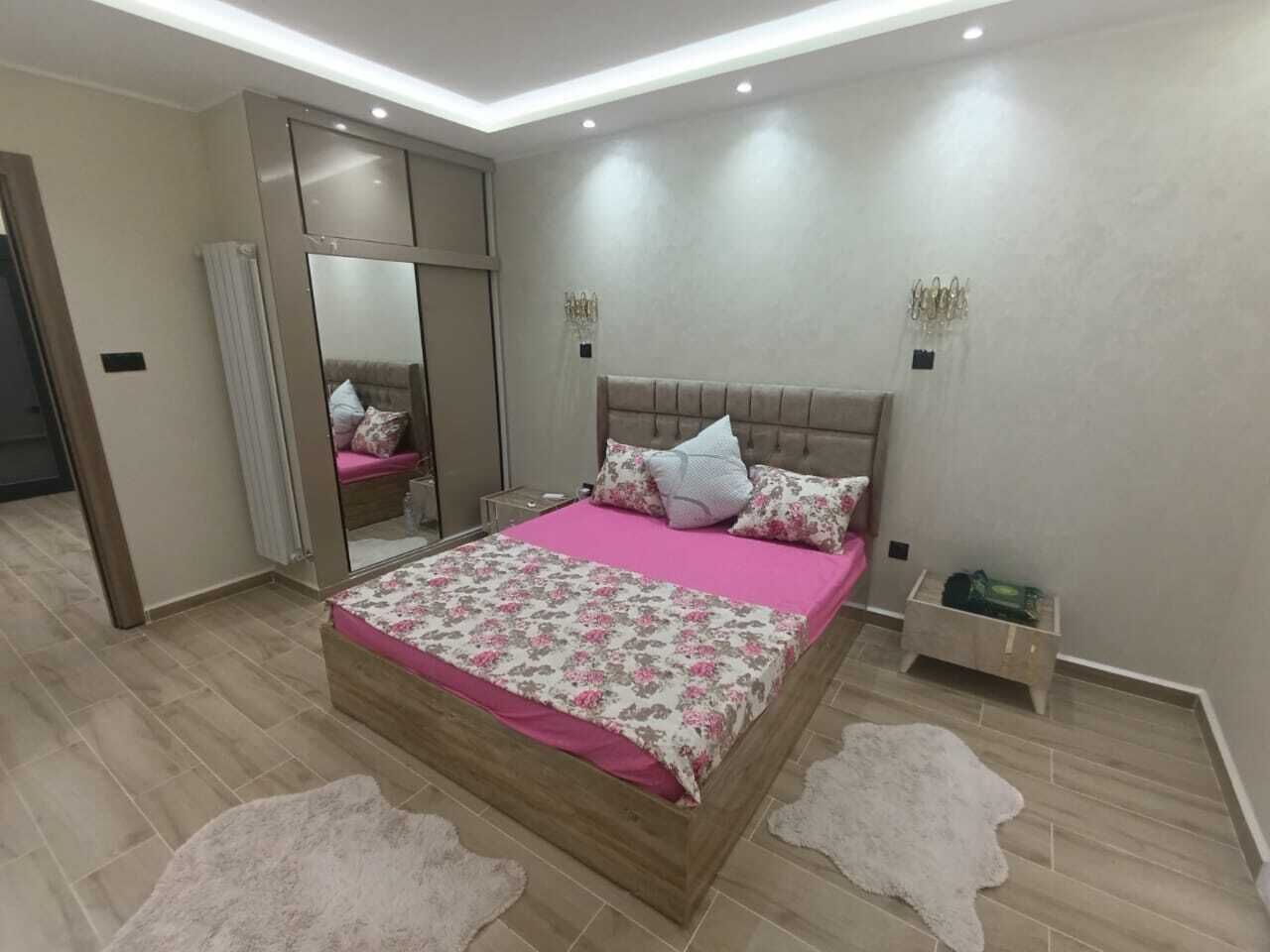 Un dormitorio con cama, un espejo, una mesita de noche y una pequeña mesa.