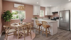 Una cocina moderna con armarios blancos, un refrigerador de acero inoxidable y un comedor con una mesa redonda y sillas.