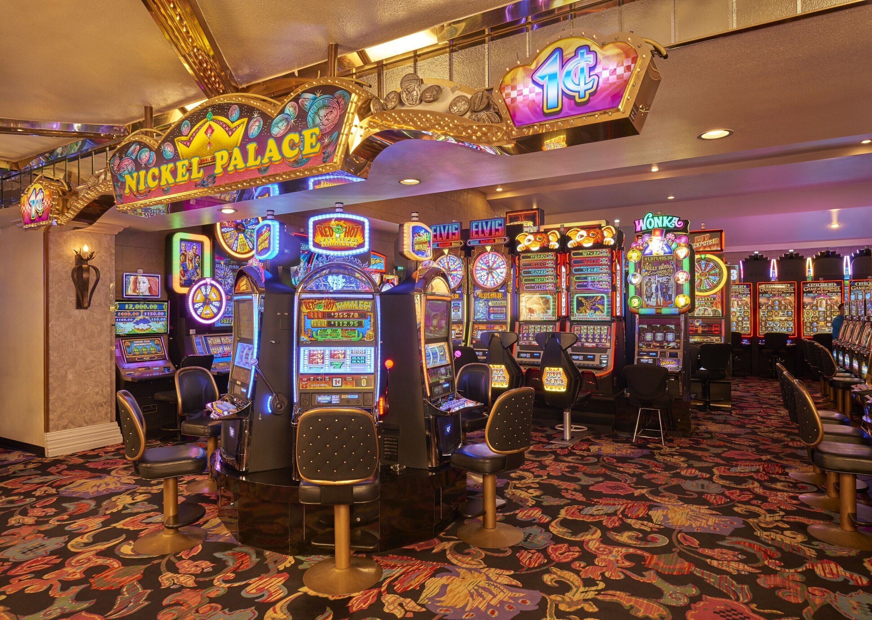 A casino with slot machines, bar stools, and neon signs.