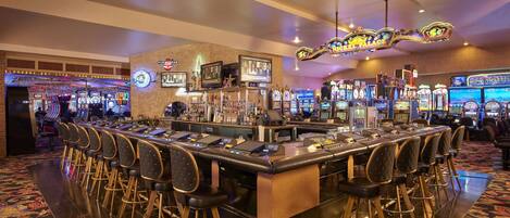 A bar area with multiple gaming machines, a bar counter, and several bar stools.