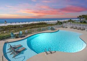 A swimming pool with lounge chairs and a view of the beach at sunset. - The Enclave 301 | Gulf Front Corner Condo | Wraparound Balcony | My Beach Getaways (Orange Beach)