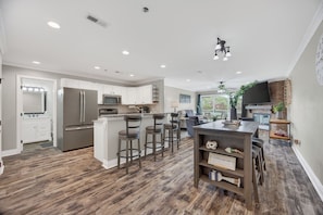 A modern kitchen with white cabinets, stainless steel appliances, and a central island with bar stools.