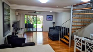 Ein geräumiger Wohnbereich mit Treppe, Esstisch und einer Couch.