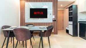 Et moderne spiseområde med et fladskærms-tv, der viser 'NETFLIX', en marmorbeklædt bagvæg og en trævæg som detalje.