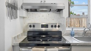 Uma cozinha com fogão de aço inoxidável, uma janela com vista e um conjunto de facas na parede.