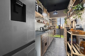 A modern kitchen with stainless steel appliances, wooden cabinets, and a view to the outside.