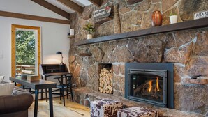 Une cheminée en pierre avec un feu de bois, un plafond en bois et une pancarte accueillante.