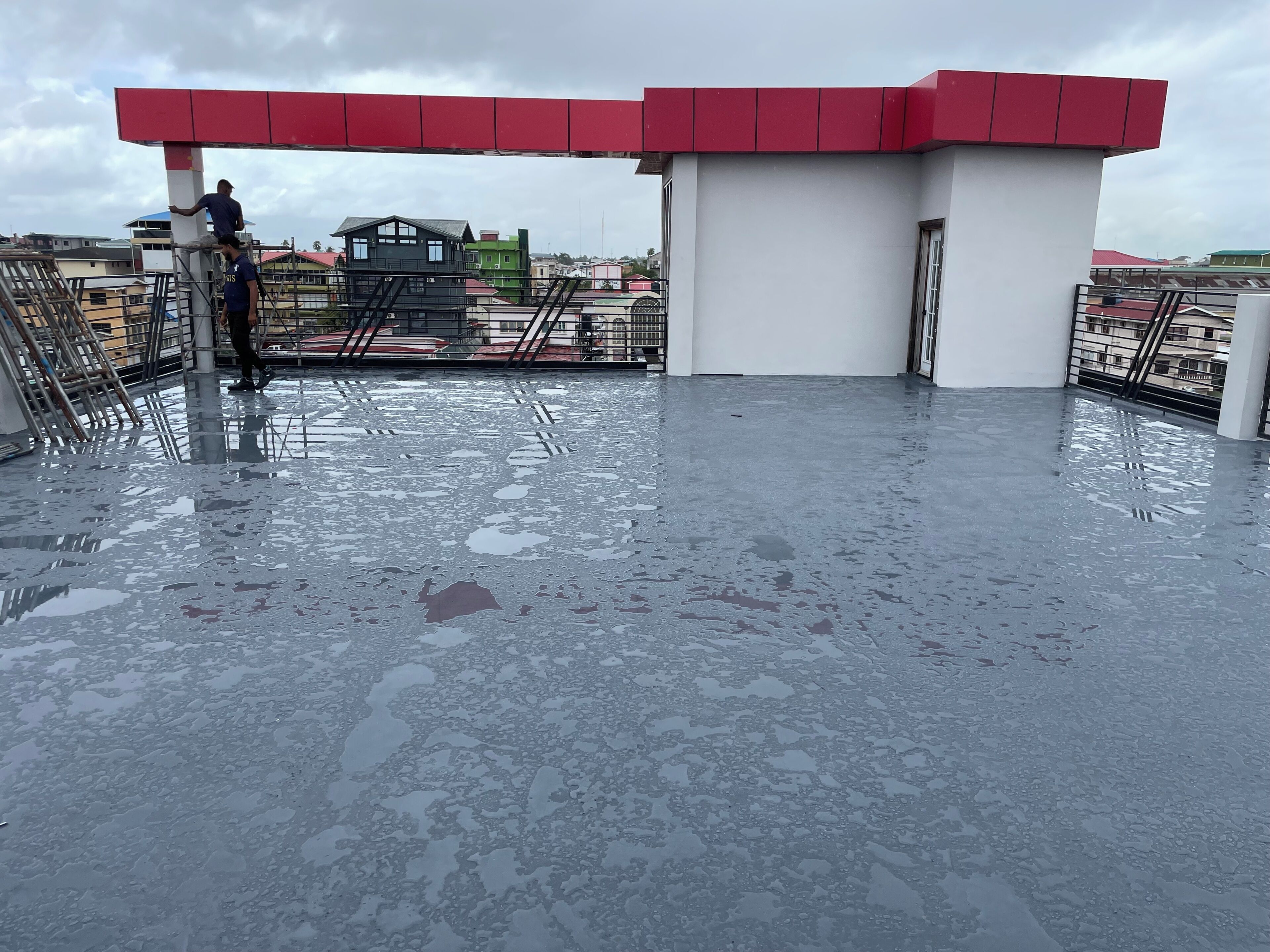 A rooftop with a red and white structure, a metal staircase, and a reflective floor.