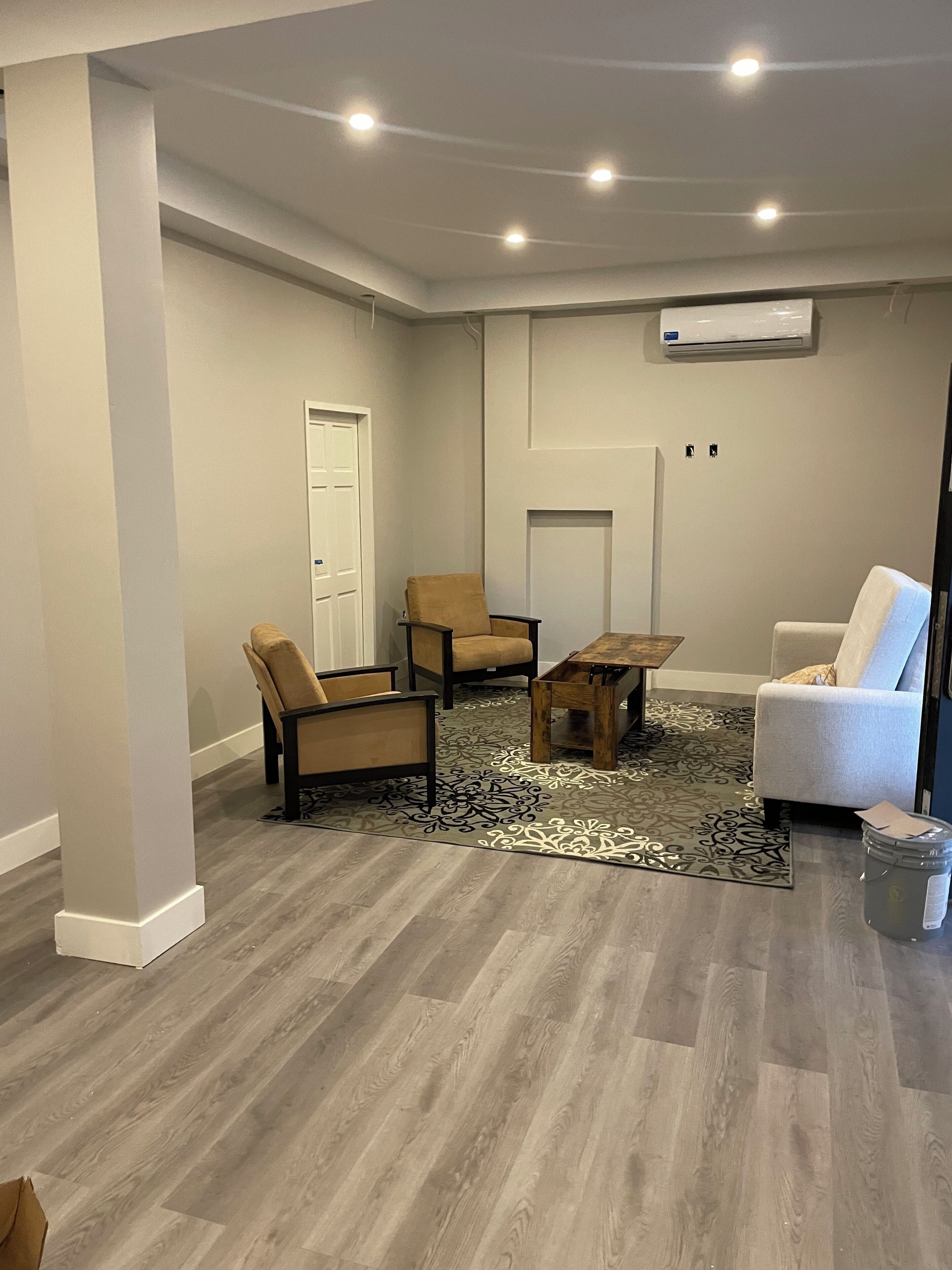 Una habitación con alfombra gris, suelo de madera, una puerta blanca y una silla blanca.