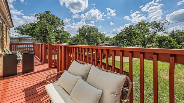 A wooden deck with a red railing, a wicker sofa with cushions, and a trash can. - Historic Oak Cliff Retreat - Yoga & Wellness Room Near Bishop Arts (Dallas)