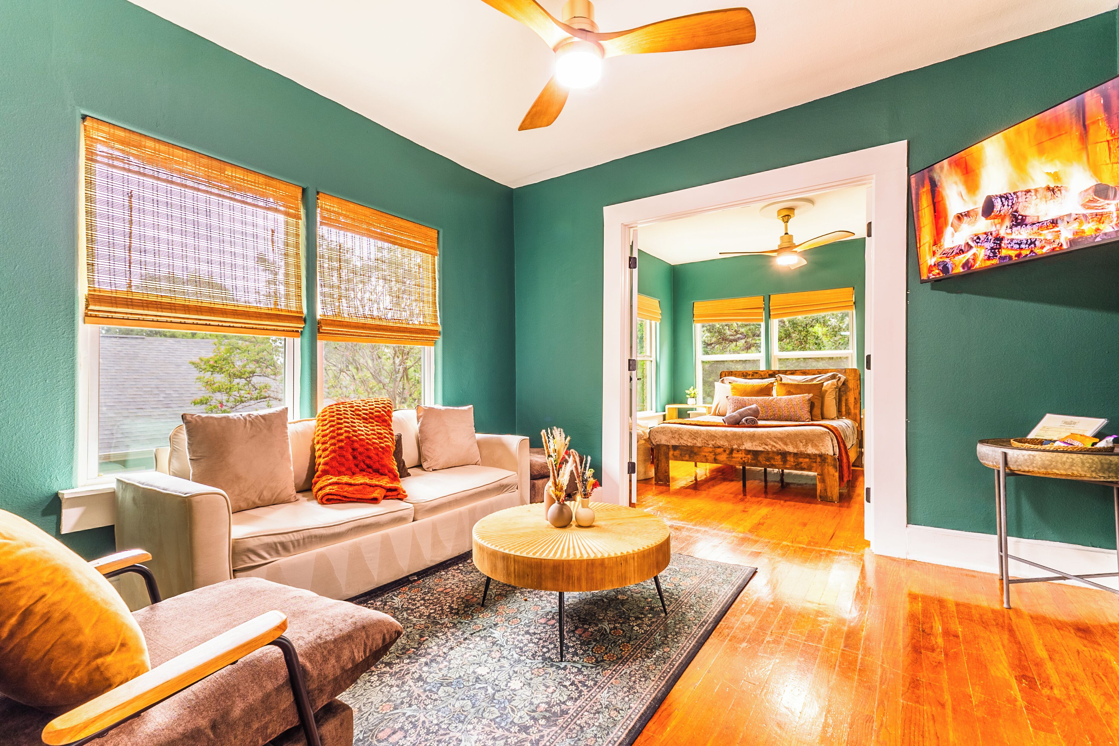 A living room with a sofa, armchair, and coffee table, a dining area with a table and chairs, and a bedroom with a bed and a nightstand.