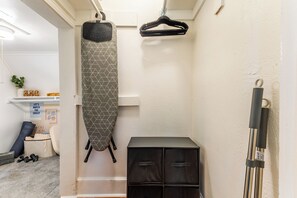 A room with a hanging garment rack, a storage unit, and a door leading to another space. - Historic Oak Cliff Retreat - Yoga & Wellness Room Near Bishop Arts (Dallas)