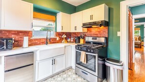A kitchen with white cabinets, a stove, and a microwave. - Historic Oak Cliff Retreat - Yoga & Wellness Room Near Bishop Arts (Dallas)