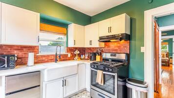A kitchen with white cabinets, a stove, and a microwave.