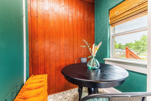 A room with a wooden door, a round table with a vase, a bench, and a window with a view. - Historic Oak Cliff Retreat - Yoga & Wellness Room Near Bishop Arts (Dallas)