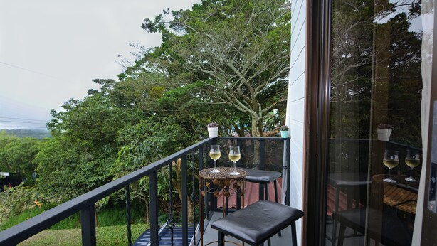 Ein Balkon mit zwei Tischen, jeder Tisch mit einem Weinglas, mit Blick auf eine üppige grüne Landschaft.