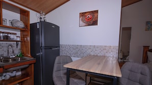 Eine kleine Küche mit Kühlschrank, Spüle und Holztisch.