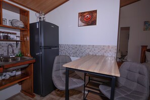 Une cuisine de taille réduite, équipée d’un réfrigérateur, d’un évier et d’une table en bois.