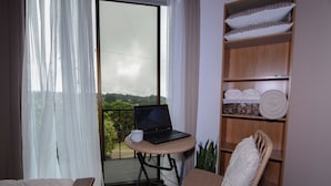 Ein Balkon mit einem Laptop, einem Stuhl und einem Regal mit Handtüchern.