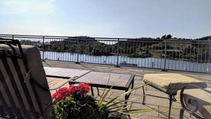 Un balcón con vista a un lago, una silla, una mesa y una planta en maceta.