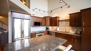 Una cocina moderna con encimeras de granito, electrodomésticos de acero inoxidable y armarios de madera.