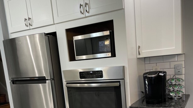 Een moderne keuken met roestvrijstalen apparatuur, witte kasten en een zwart aanrecht.