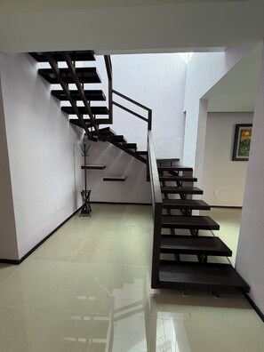 A modern staircase with a metal railing, a wall-mounted coat rack, and a framed picture on the wall. - Large luxury house with 6 bedrooms pool and jacuzzi (Cancún)
