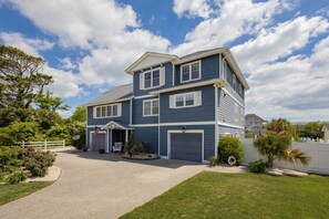 Ein zweistöckiges Haus mit Auffahrt, Garage und einem Vorgarten mit Bepflanzung.