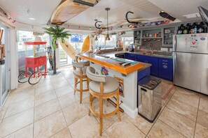 Eine Küche mit Bar, Kühlschrank und Mülleimer.