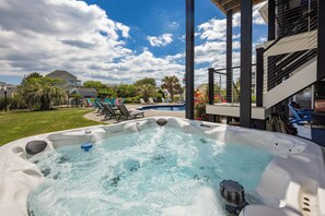 Ein Whirlpool mit Blick auf einen Pool und eine Außenbereich-Sitzgelegenheit.
