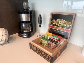 A coffee maker, a coffee grinder, and a box of Perdomo Churchill brand coffee. - Cozy 1-bedroom condo in tranquil Pompano Beach with AC (Pompano Beach)