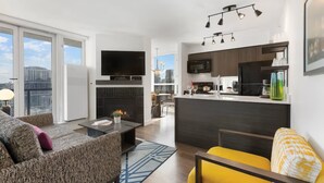En modern lägenhet med vardagsrum, kök och matplats, utrustad med öppen spis, platt-TV och utsikt över staden.