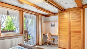 A bedroom with a bed, a desk, a chair, and a wardrobe. - Haus Schmid - Apartment Dompfaff with Mountain View, East Balcony, Wi-Fi (Lenzkirch)