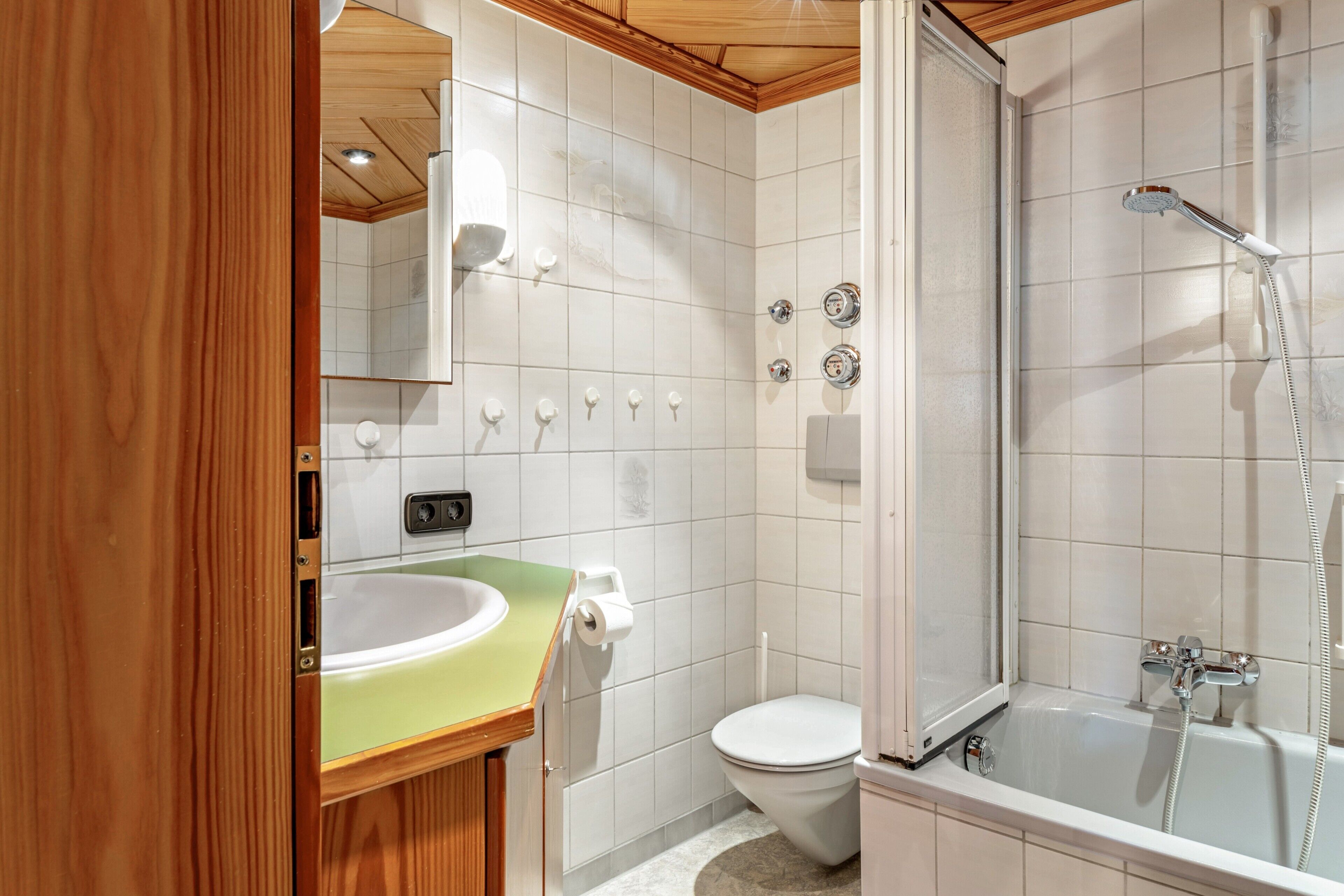Un baño con lavamanos, inodoro, ducha y espejo.