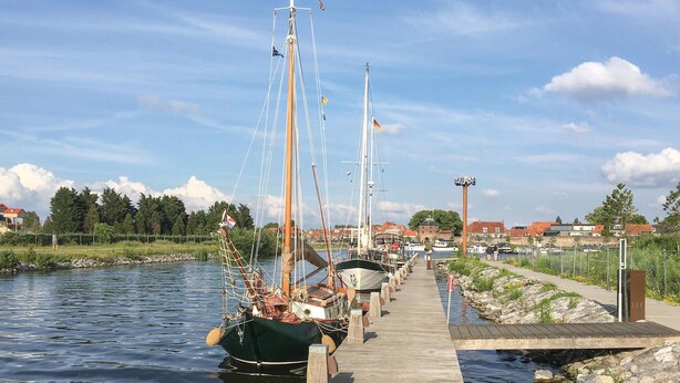 Un muelle de madera que se extiende sobre aguas tranquilas, con varias embarcaciones amarradas a lo largo.