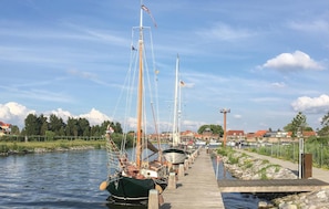 A wooden dock extending into calm water with several boats moored along it.
