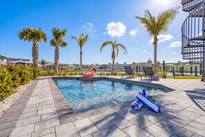 A swimming pool with lounge chairs and palm trees. - Stylish Waterfront Escape with Pool, Steps to Beach & Sunset Views - Casa Laguna 4 - Roelens (Fort Myers Beach)